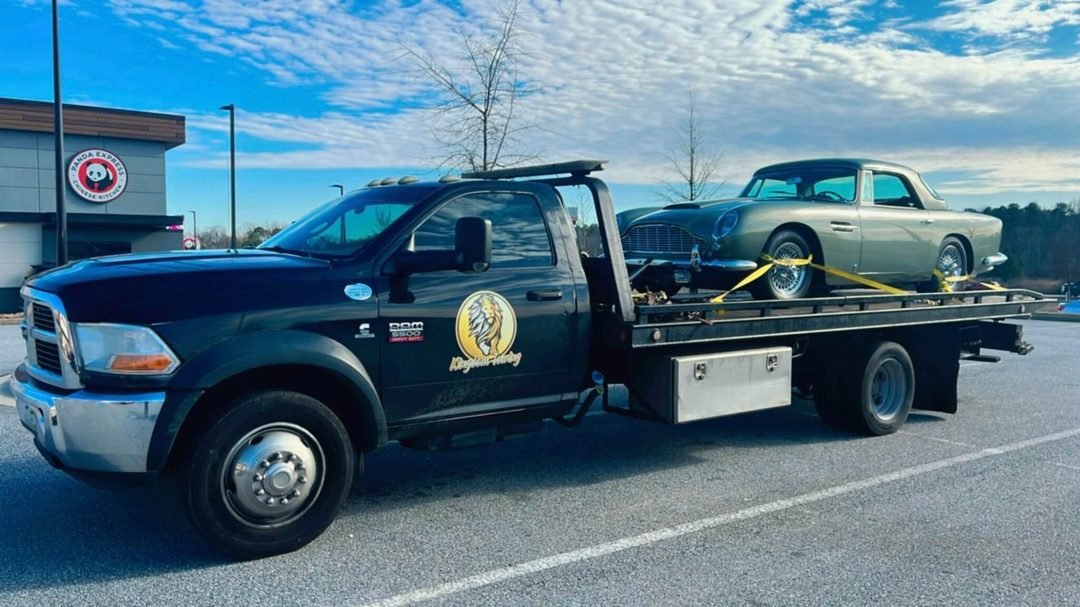 Kingdom Towing flatbed truck loaded with a vehicle on an Atlanta road at sunset